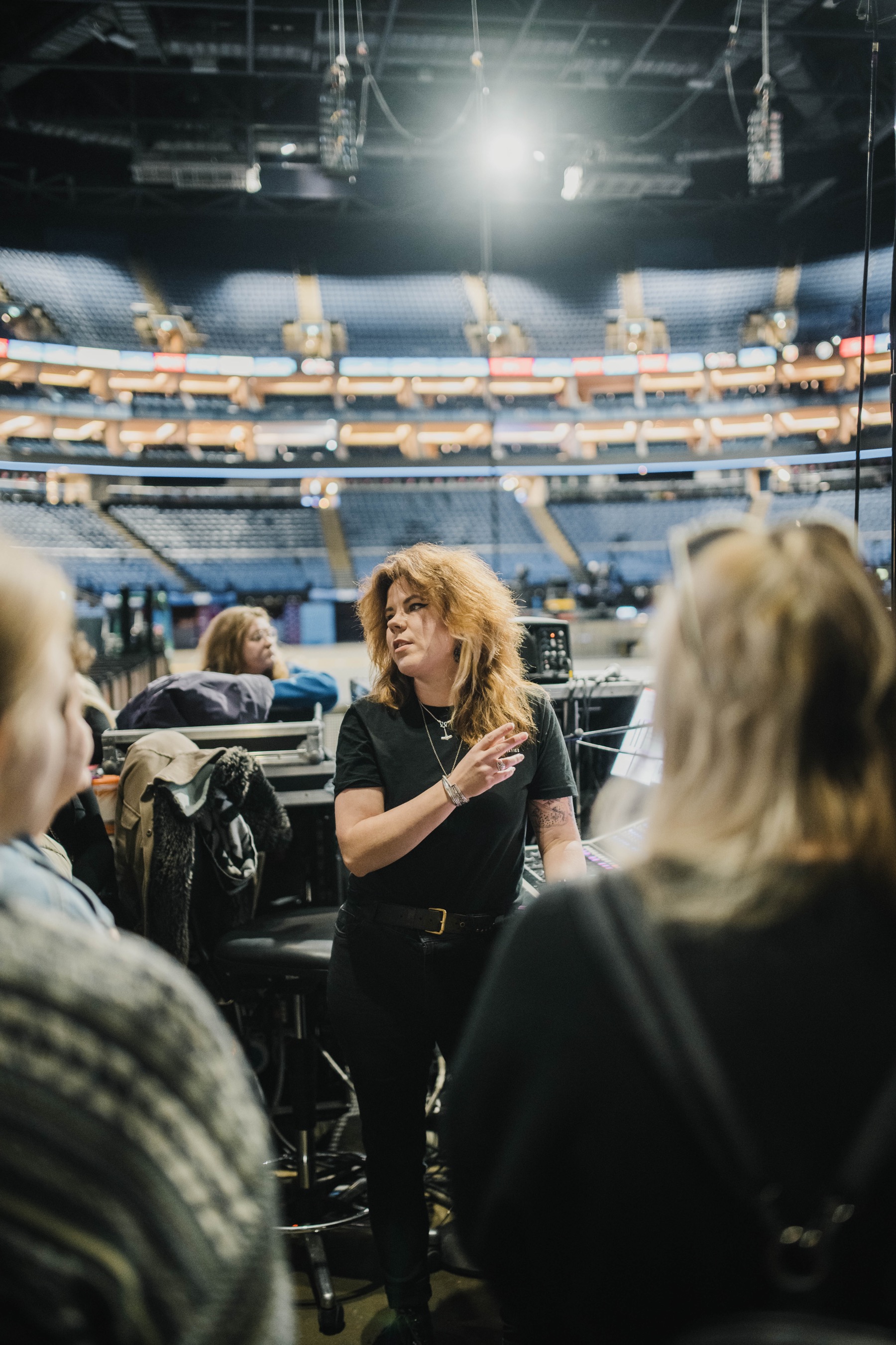Hannah Brodrick speaking with a group beside a live sound console